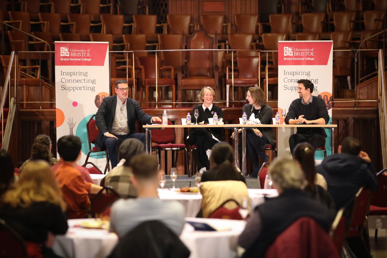 three panellists sit on a stage to discuss the future of the PhD